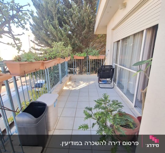 מרפסת עם עציצים, כיסא נדנדה ופחי אשפה